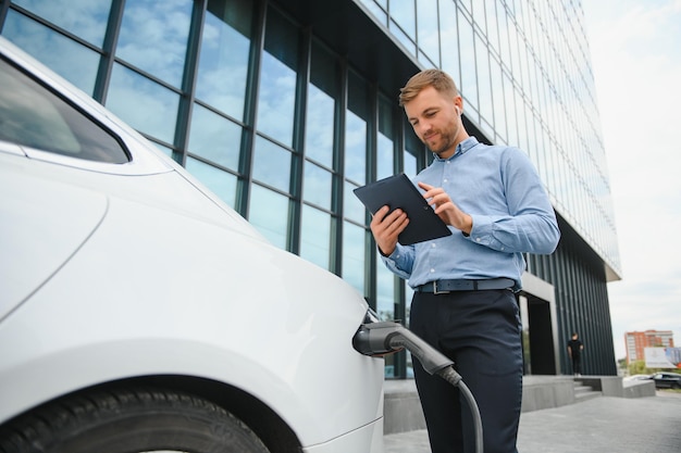 Un empresario carga un coche eléctrico.