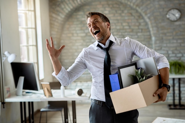 Empresario cargando sus pertenencias y gritando de frustración tras perder su trabajo