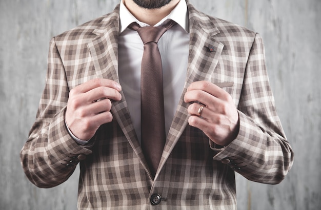 Empresario con chaqueta y corbata marrón de pie en la oficina.