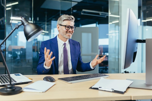 Empresário chefe irritado e chateado gritando com monitor de computador homem com óculos trabalhando no escritório moderno no computador