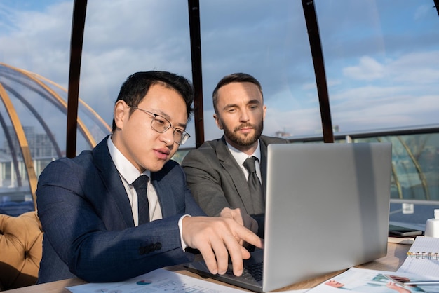 Empresário chinês confiante apontando para a tela do laptop