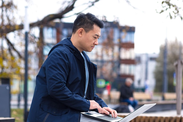 Empresario chino que trabaja en línea de forma remota en una computadora portátil hombre asiático fuera de la oficina