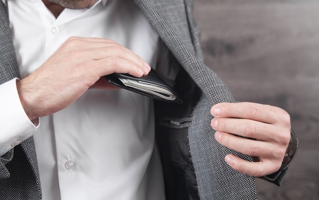 Empresário colocando carteira com notas no bolso do terno.