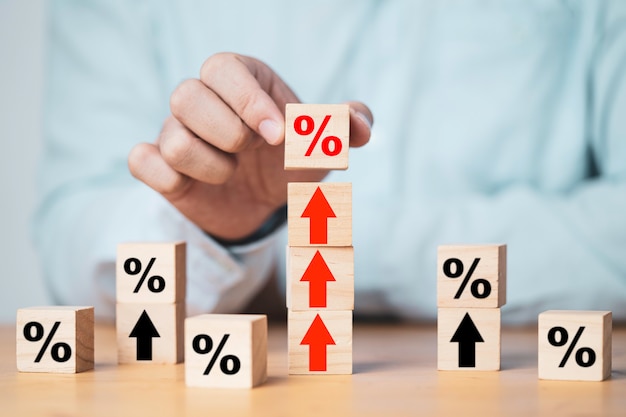 Empresário, colocando o sinal de porcentagem que imprime a tela em um bloco de cubo de madeira para cima seta para o lucro do negócio e o conceito de crescimento econômico.