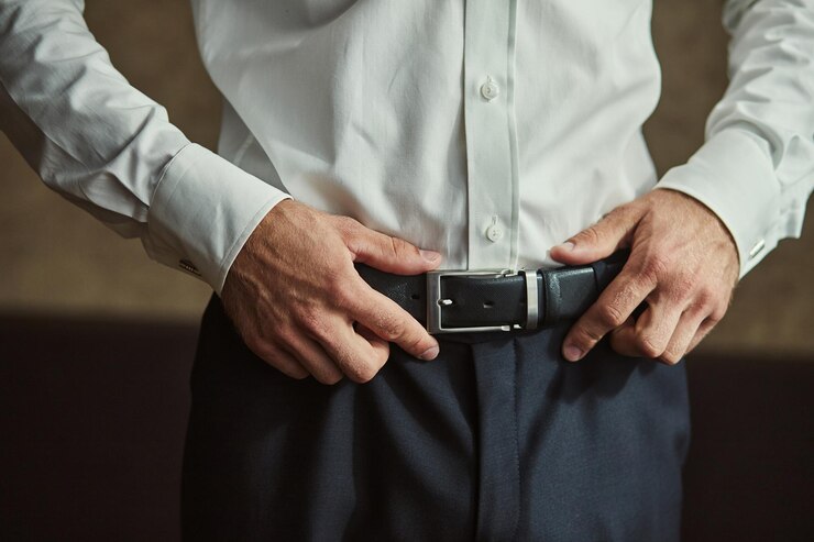 Empresário colocando um cinto de moda e vestuário conceito noivo se preparando de manhã antes da cerimônia