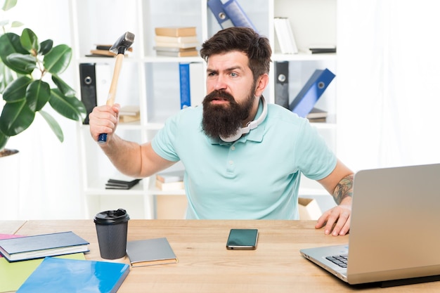 Empresário com barba e bigode enlouquecido com martelo na mão Empresário agressivo irritado no escritório Trabalhador de escritório frustrado segurando o martelo pronto para esmagar A vida no escritório o deixa louco