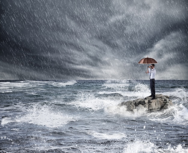 Foto empresário com guarda-chuva durante uma tempestade no mar