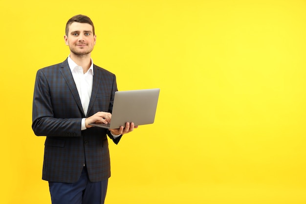 Empresário com laptop em fundo amarelo, espaço para texto.