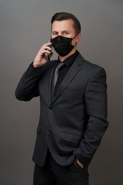 Foto empresário com máscara médica cirúrgica usando telefone celular