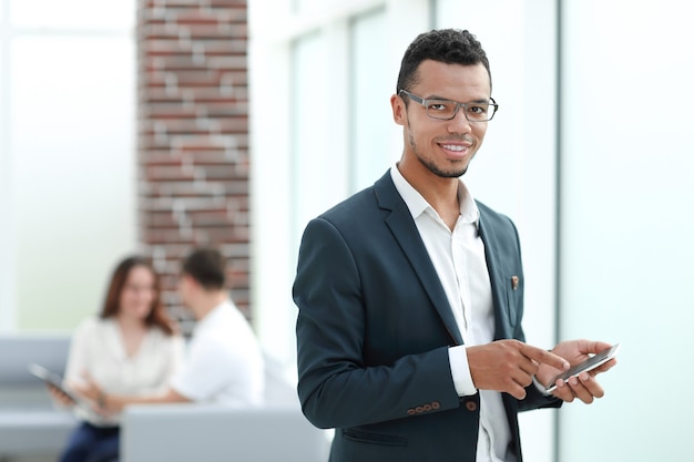 Empresário com smartphone em pé no escritório moderno.