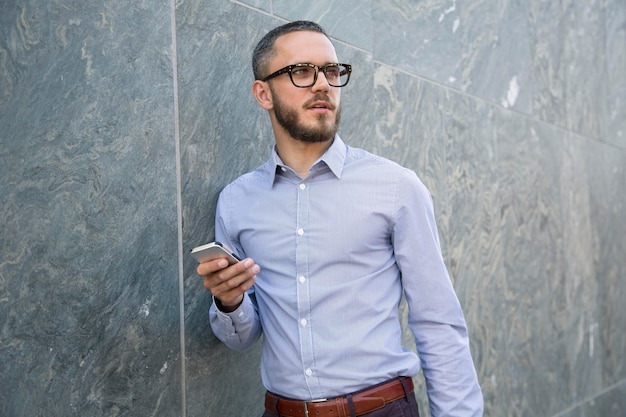 Empresário com telefone celular ao ar livre olhando de soslaio