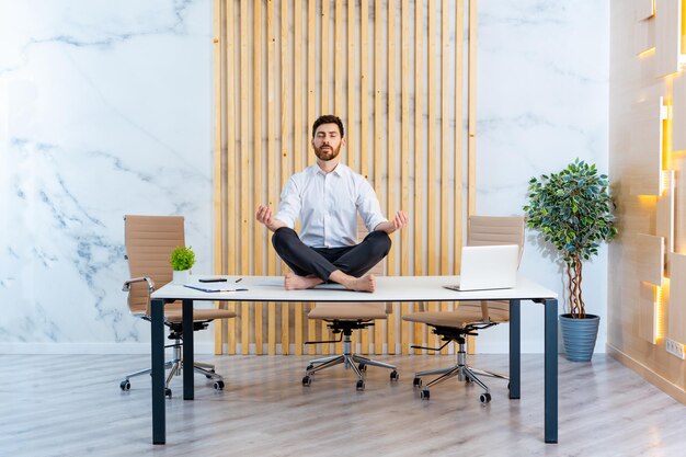 Empresário com terno elegante sentado na mesa do computador no escritório meditando