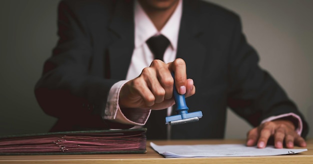 Foto empresário com um selo de aprovação em um documento de certificado de reconhecimento de firma público em sua mesa advogado aprovação de contrato de aceitação de contrato de uso condições de seleção acordo de carimbo