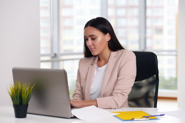 Empresário com uma jaqueta rosa sentado em um laptop no escritório