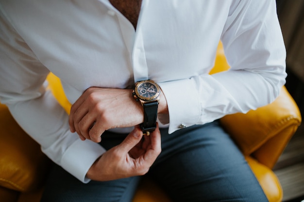 Empresario comprobando el tiempo en su reloj de pulsera, el hombre poniendo el reloj en la mano, el novio preparándose en el