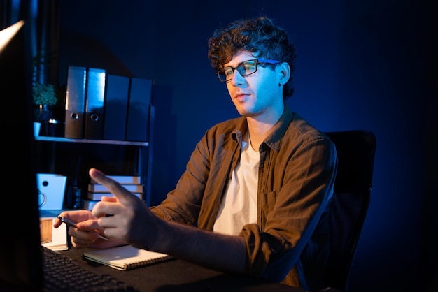 Empresario concentrado en la computadora en un proyecto en la oficina de luz de neón Gusher