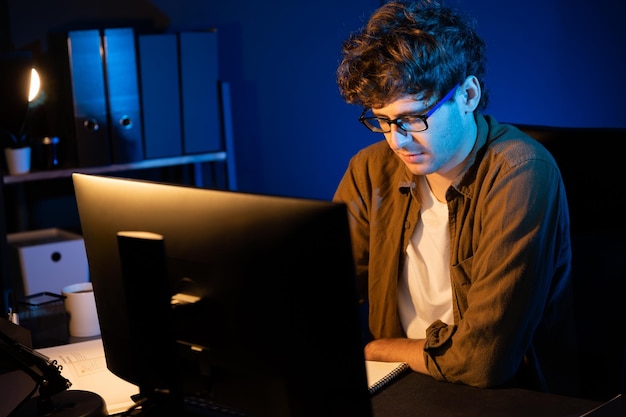 Empresario concentrado en la computadora en un proyecto en la oficina de luz de neón Gusher