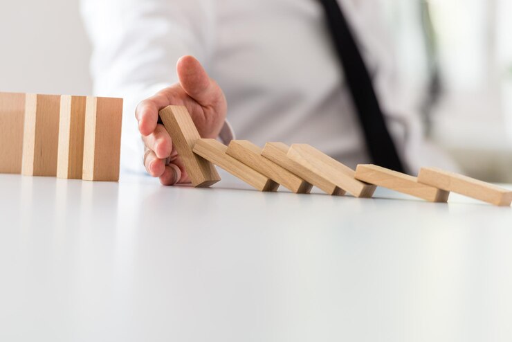 Foto empresario de concepto de intervención empresarial poniendo fin a un dominó que se derrumba con la mano