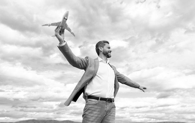 Empresário confiante e feliz na jaqueta segura avião de brinquedo no sucesso comercial do fundo do céu