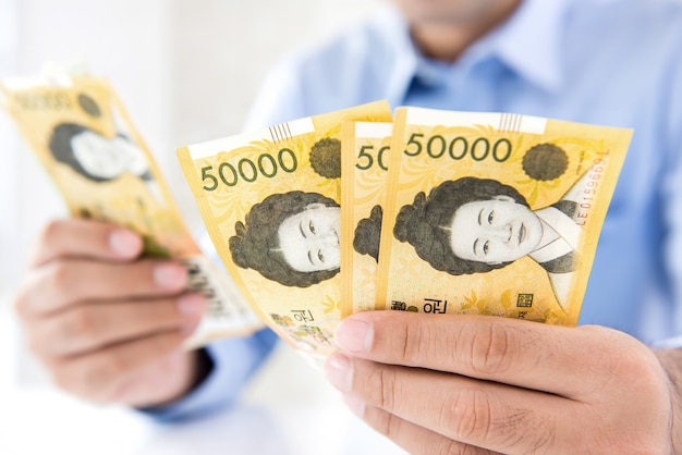 Empresário contando dinheiro notas de won sul-coreano em suas mãos
