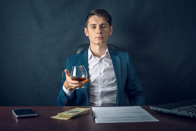 Empresario con una copa de vino sentado en un escritorio