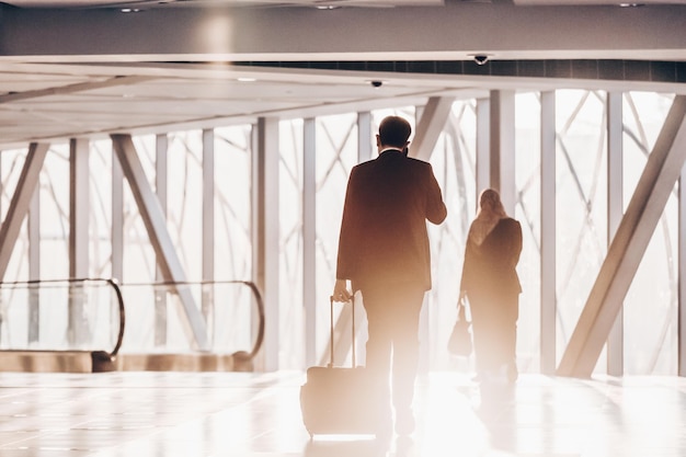 Empresario en el corredor del aeropuerto caminando hacia las puertas de embarque