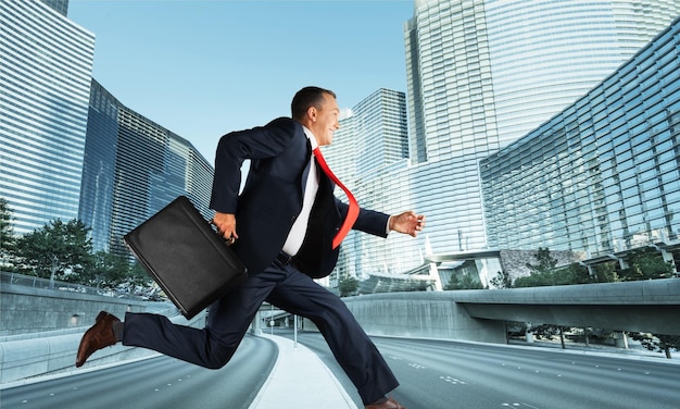 Foto empresario corriendo con maletín en el fondo de la ciudad