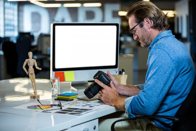 Empresário criativo segurando a câmera na mesa do computador