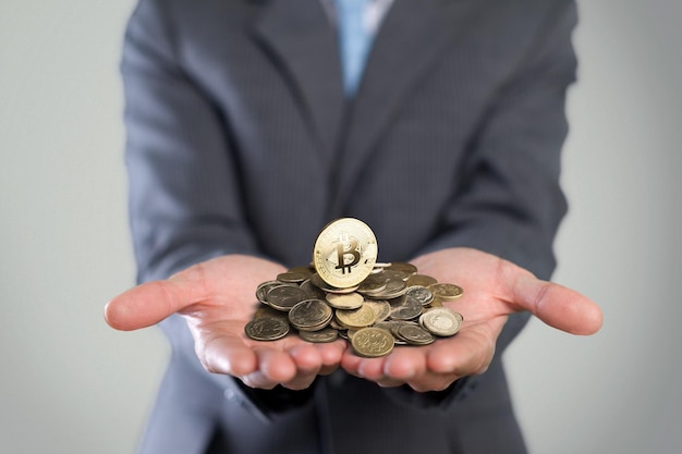 Empresário dando bitcoin dourado para outro humano. duas mãos trocando criptomoeda.