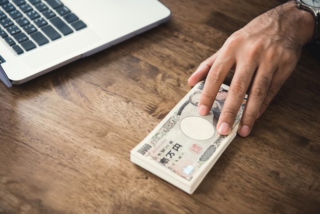 Empresário dando dinheiro de notas de ienes japoneses em cima da mesa