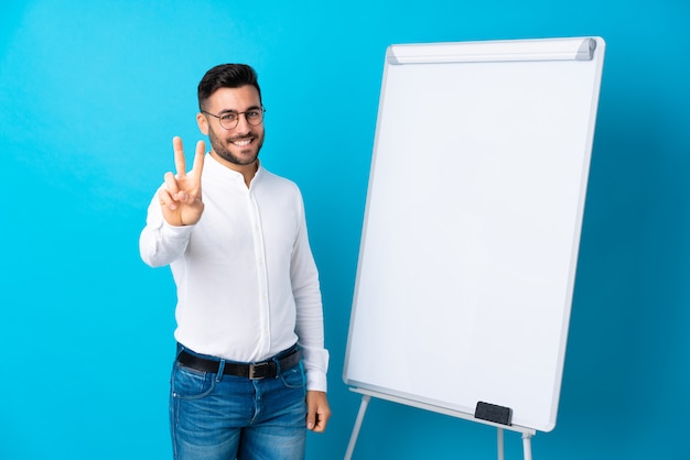 Empresário, dando uma apresentação no quadro branco, dando uma apresentação no quadro branco e mostrando sinal de vitória