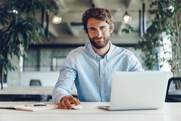 Empresário de camisa trabalhando em seu laptop em um escritório. Escritório de espaço aberto