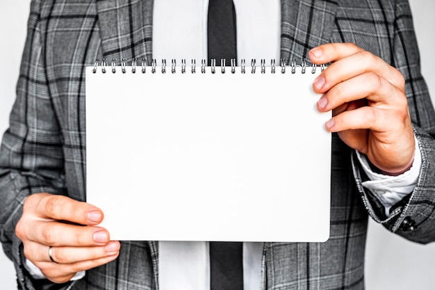Empresário de conceito de internet e rede de tecnologia de negócios em terno cinza elegante segurando um caderno branco modelo para inscrição