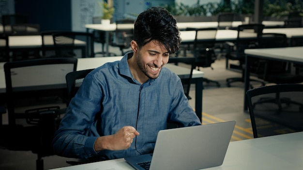 Empresário de meia-idade de 30 anos no escritório trabalhando em laptop celebra sucesso de lucro de crescimento de carreira