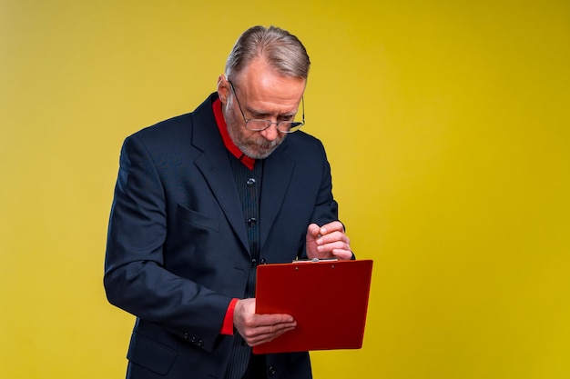 Empresário de meia idade em pé e segurando a pasta de arquivos Verificando notas Formato horizontal isolado em fundo amarelo