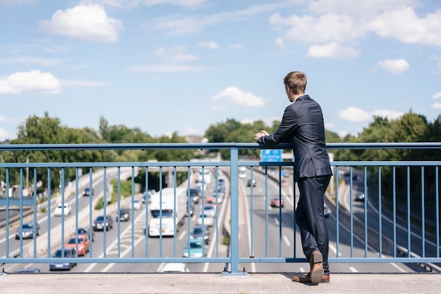 Empresário de pé em uma ponte sobre uma auto-estrada