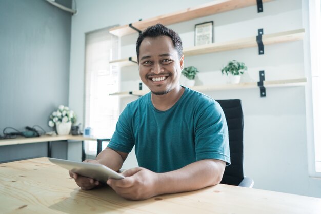 Empresário de sorriso obter um sucesso para seus negócios e mãos segurando um tablet olhar para a câmera