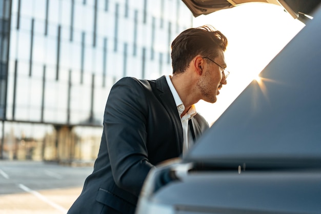 Empresário de sucesso tirando bagagem do porta-malas do carro