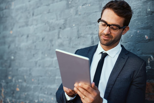 Empresário de tablet e leitura de notícias com confiança ou orgulho como contabilista agência financeira Pessoa masculina consultor financeiro e pesquisando oportunidades de investimento com ideias de tecnologia e parede cinza
