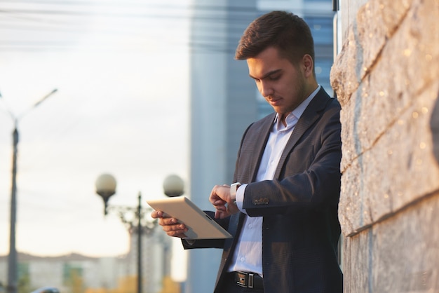 Foto empresário de terno e tablet na mão procurando a outra mão com o relógio