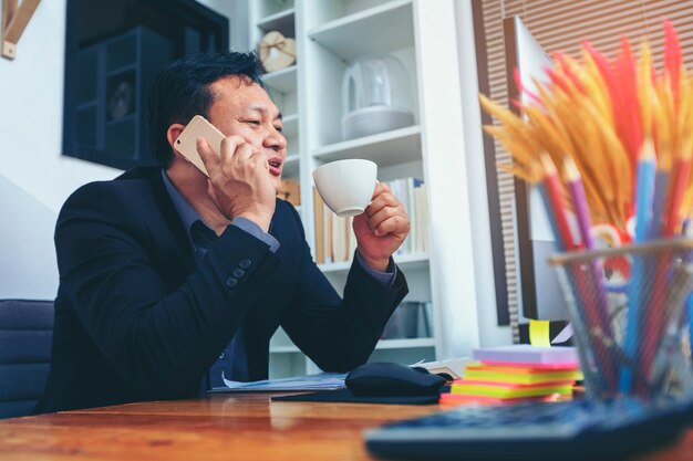 Empresário de terno falando no telefone trabalhando no computador