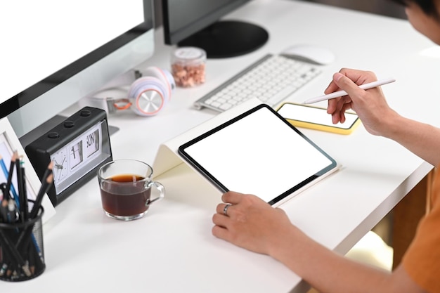 Empresário de tiro recortado segurando a caneta stylus e trabalhando na mesa digital no espaço de trabalho moderno