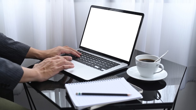 Empresário de tiro recortado sentado em seu quarto e trabalhando com o laptop.