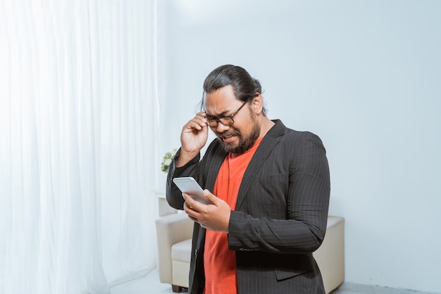 Empresario decepcionado recibiendo mensajes de texto en su teléfono inteligente