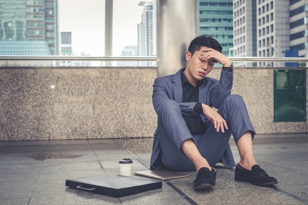 Empresario deprimido y cansado sentado en la ciudad