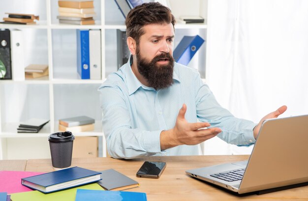 Empresário desapontado trabalhando no laptop no trabalho de mesa de escritório