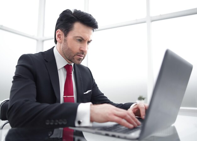 Empresário digitando em um laptop sentado em sua mesa