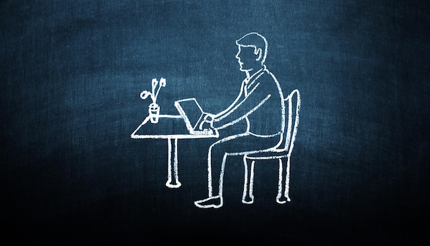 Empresário digitando em um laptop sentado em um desenho de quadro-negro de mesa