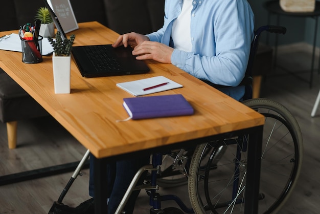 Foto empresario discapacitado sentado en silla de ruedas y usando la computadora en la oficina