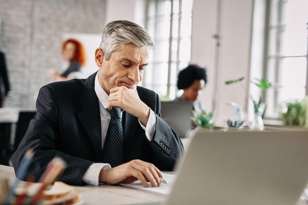 Empresario disgustado revisando papeleo y leyendo informes comerciales en el trabajo